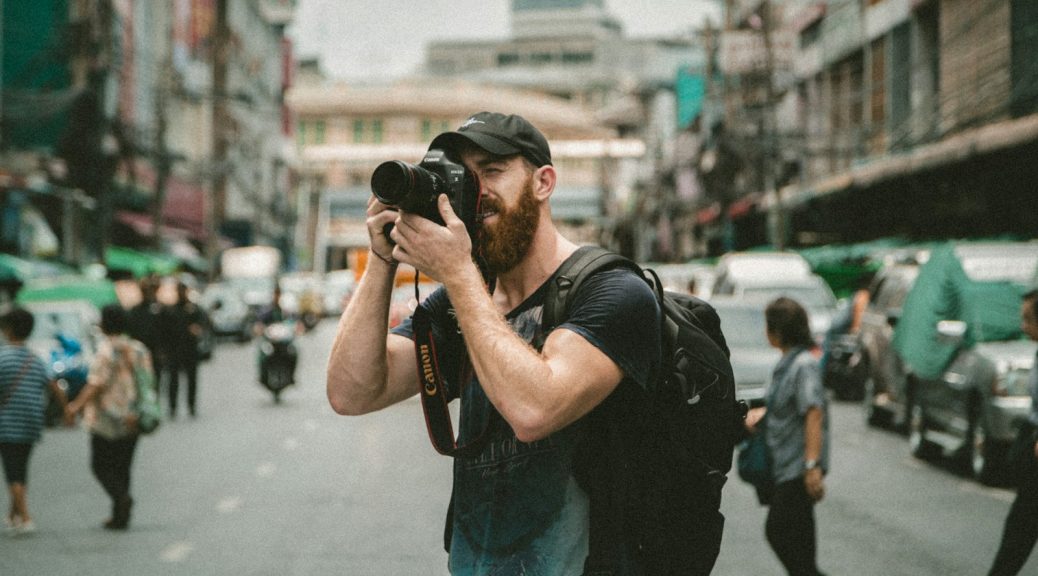 shallow focus photography of man using a DSLR camera